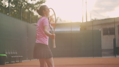 Professional-equipped-female-beating-hard-the-tennis-ball-with-tennis-racquet.-Female-tennis-player-in-action-during-game.-She-is-wearing-unbranded-sport-clothes.